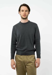 Grauer Strickpullover mit rundem Halsausschnitt und langen Ärmeln, ausgestattet mit einem gerippten Saum. Das Material scheint weich mit einer glatten Textur zu sein.