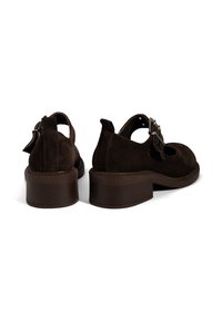 Braune Wildlederschuhe mit einer abgerundeten Spitze und ausgeschnittenen Seiten. Sie verfügen über einen niedrigen, gestapelten Absatz und dekorative Schnallenakzente.