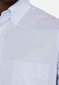 Koszula na guziki w jasnoniebieskie i białe cienkie paski, z ostrym kołnierzykiem i kieszenią na piersi po lewej stronie.