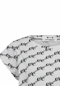 Tricou alb cu un model grafic negru repetitiv, mâneci scurte și guler rotund. Eticheta spune "co'couture."