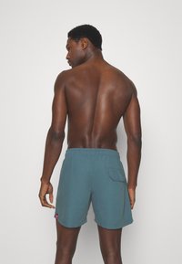 Șorturi de înot pentru bărbați culoare teal, cu un brâu elastic și un buzunar posterior. Materialul pare neted, având o textură ușoară.