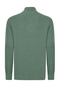 Grøn ribstrikket sweater med opretstående krave og lange ærmer. Teksturen er glat, og stoffet virker blødt og hyggeligt.