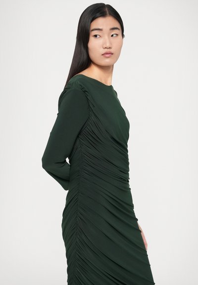 Ciemnozielona sukienka z długimi rękawami, okrągłym dekoltem i marszczeniem po bokach. Tkanina wygląda na gładką, z teksturowanym, marszczonym wzorem.