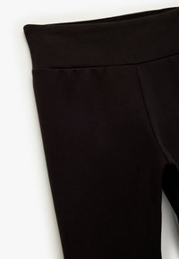 Zwarte leggings van een gladde, rekbare stof. Voorzien van een brede, elastische tailleband en een getailleerd silhouette zonder zichtbare naden.