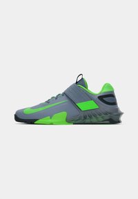 Sapatilha atlética cinza com realces em verde fluorescente, apresentando um design aerodinâmico, parte superior texturizada e forma de solado distinta.