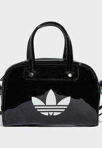 Sac à main en cuir verni noir, de forme arrondie, avec poignées doubles et logo trèfle Adidas blanc sur le devant. Dispose d'une fermeture éclair.