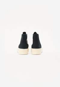 Tenisi negri cu guler înalt, cu un superior din pânză, talpă din cauciuc de culoare deschisă și o etichetă logo pe călcâi. Vederea din spate arată linii curate și un design minimalist.
