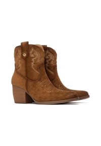 Botas de tobillo de ante marrón con una forma cónica, costuras decorativas, lengüetas y un tacón grueso con surcos horizontales.