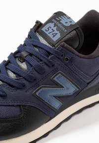 Marineblaue Sneaker mit schwarzen Lederelementen, strukturiertem Stoff und grauen Logodetails. Mit flachen Schnürsenkeln und einer gepolsterten Sohle.
