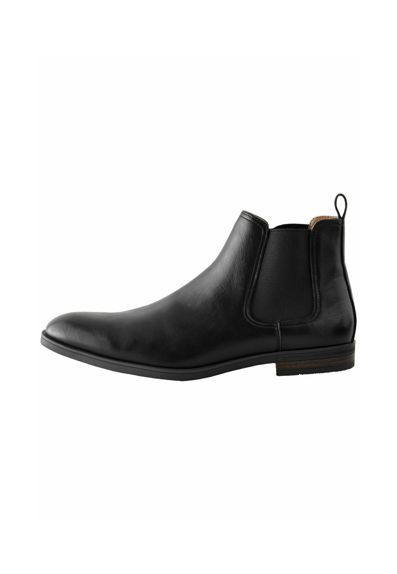 Bota Chelsea de cuero negro con paneles laterales elásticos, textura suave, punta redondeada y un acento marrón en el talón.