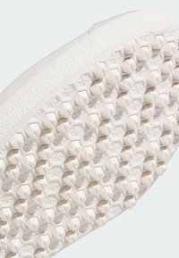 White shoe sole featuring a textured surface with star-shaped patterns and small hexagons for grip. Made of rubber material.