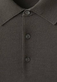 Ciemnoszara dzianinowa koszulka polo z trzema czarnymi guzikami i prążkowanym kołnierzykiem, pokazana z bliska.