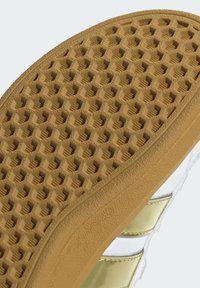 Guma đonjište s uzorkom saća, s teksturiranom smeđom površinom. Akcentirano glatkim zlatnim i bijelim gornjim dizajnom.