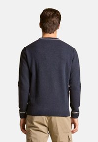 Maglione a maglia blu navy con polsini e orlo a coste, caratterizzato da un collo a giro e un elegante bordo più chiaro al colletto. Tessuto testurizzato chiaramente visibile.