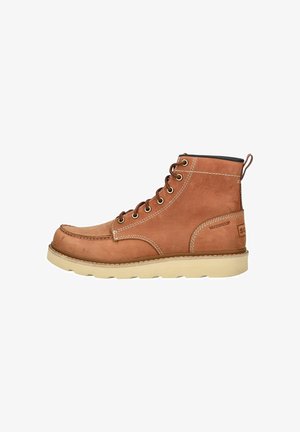 Stivale alla caviglia in pelle impermeabile marrone con cuciture bianche, punta rotonda e suola in gomma beige chiaro. Presenta occhielli in metallo e linguetta per facilitare l'indossamento.
