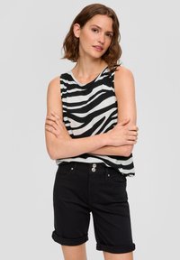 Zwart-wit gestreepte mouwloze top van zachte stof, gecombineerd met opgerolde zwarte shorts met een knoopsluiting en zakken.