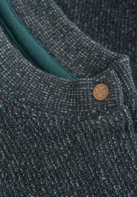 Gestructureerde donkerteal en grijze sweaterstof met een geribde hals, voorzien van een groene binnenvoering en een klein bruin knoopdetail.