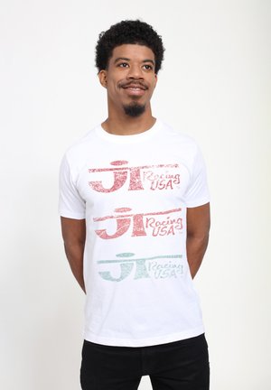 T-shirt blanc avec trois impressions graphiques horizontales en rouge et vert, arborant "Racing USA" dans un style vintage. Manches courtes, design col rond.