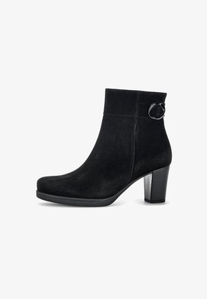 Bottines en suède noir avec un bout arrondi, une couture à l'avant, une boucle décorative et un talon épais. Texture lisse avec une finition mate.