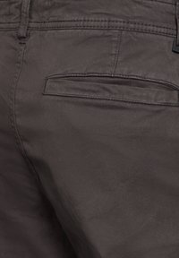 Mörkgrå byxor med en slät yta, subtil lyster, en bakficka med horisontell öppning och kontrasterande sömnadsdetaljer.