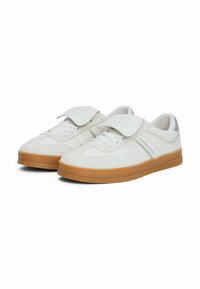 Baskets blanches avec une tige en daim et en cuir, dotées d'une sangle en velcro, d'un laçage à l'avant et d'une semelle en caoutchouc couleur gomme. Accentuées par "TOMMY JEANS."