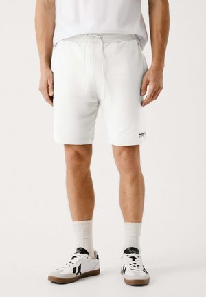 Hvide træningsshorts med elastisk talje og snøring, har sidelommer og et lille sort logo på venstre lår.