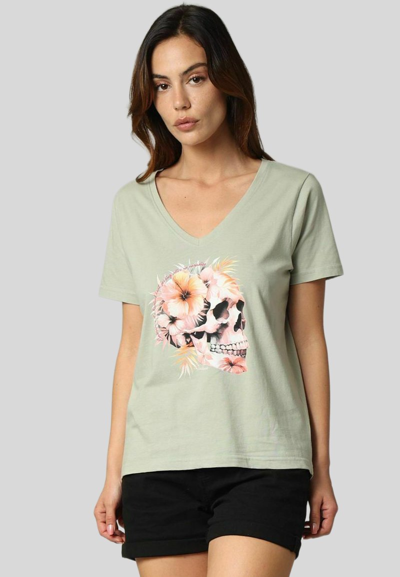 T-shirt en coton vert clair avec un col en V. Présente un design de skull imprimé orné de fleurs roses. Manches courtes, coupe décontractée.
