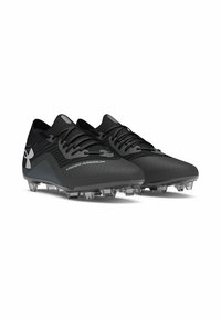 Botas de fútbol negras con un upper texturizado, diseño elegante, cordones y tacos transparentes. Presentan la marca Under Armour en color plateado.