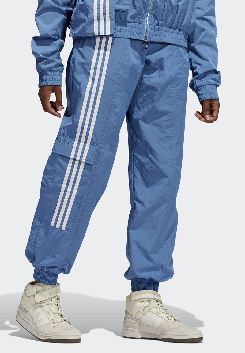 Lichtblauwe windbreaker en bijpassende joggerbroek van lichtgewicht stof, met drie witte strepen langs de zijkanten en elastische boorden.