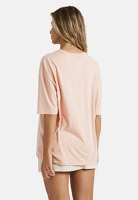 Kortærmet t-shirt i ferskenfarve med løs pasform, lavet af blødt bomuldsstof. Har rund halsudskæring og ensfarvet bagside.