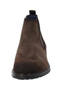 Bottines en daim marron avec des panneaux élastiques sur les côtés, bout arrondi et semelle en caoutchouc noire, présentant des coutures le long des bords.
