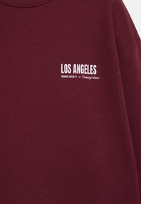 Bordeaux sweatshirt met witte opdruk: "LOS ANGELES," "HONOR SOCIETY," en "Training Season." Zacht materiaal, ronde halsontwerp.