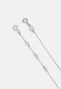 Silverfärgad kedjehalsband med en klar geometrisk hänge och en låsning med oktagonal design. Kedjan har små länkar och klar detaljer.