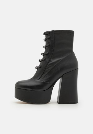 Schwarze high-heeled Stiefeletten mit einer dicken Plattform, aus glattem Leder gefertigt, mit einer schnürbaren Vorderseite, metallischen Ösen und einem stabilen Blockabsatz.