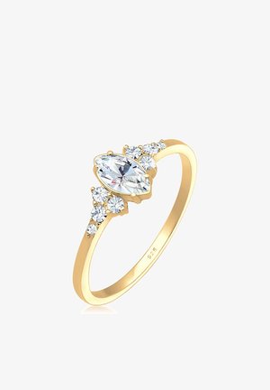 Bague en or présentant une pierre centrale en taille marquise, flanquée de pierres rondes, avec un anneau poli et des détails fins. Fabriquée en argent sterling.