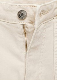 Bež bombažne hlače s srebrnim zadrgo in gumbom za zapiranje. Imajo močno teksturo tkanine in šive ob pasu ter šivih.