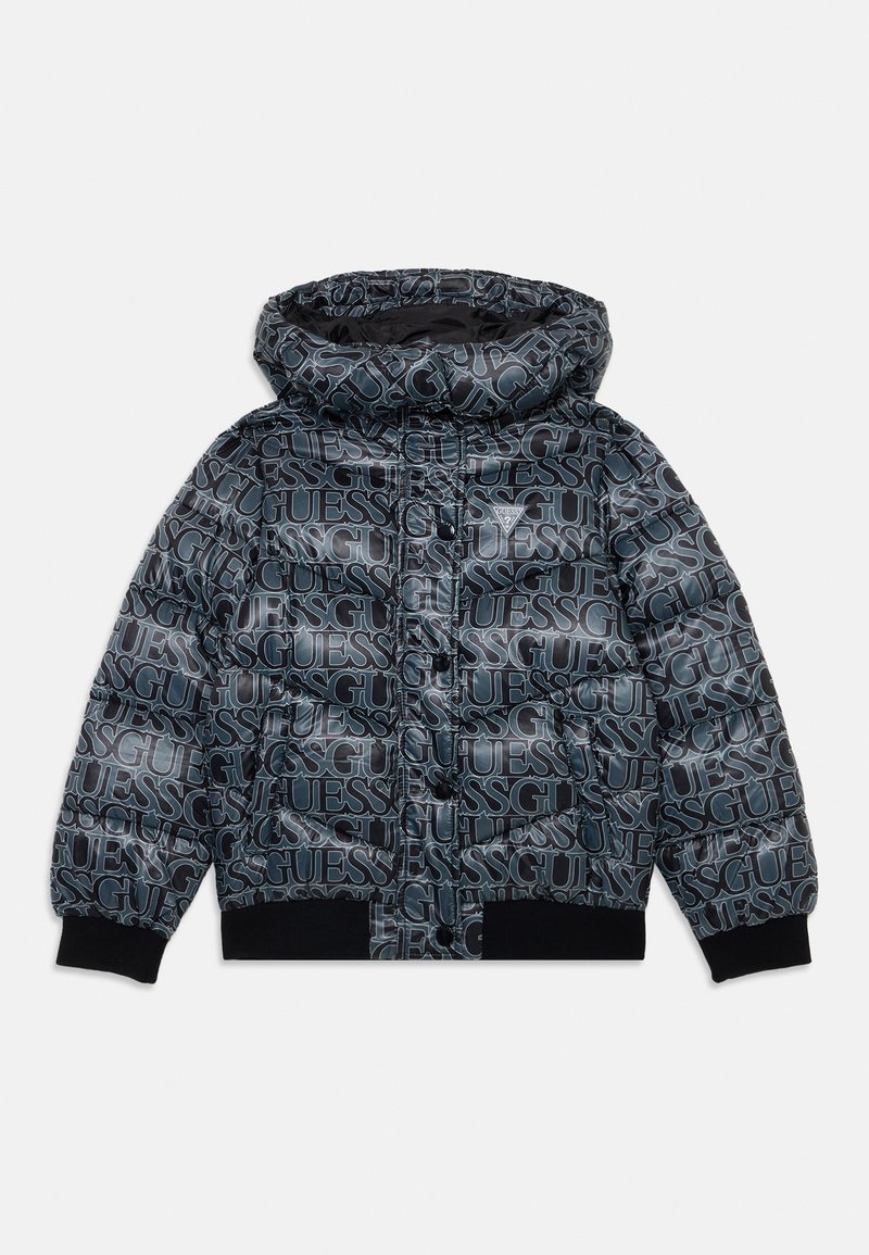 Chaqueta acolchada en negro con impresión repetida del logo "GUESS", presenta una capucha, cierre de cremallera y puños y dobladillo elásticos. Textura mate.