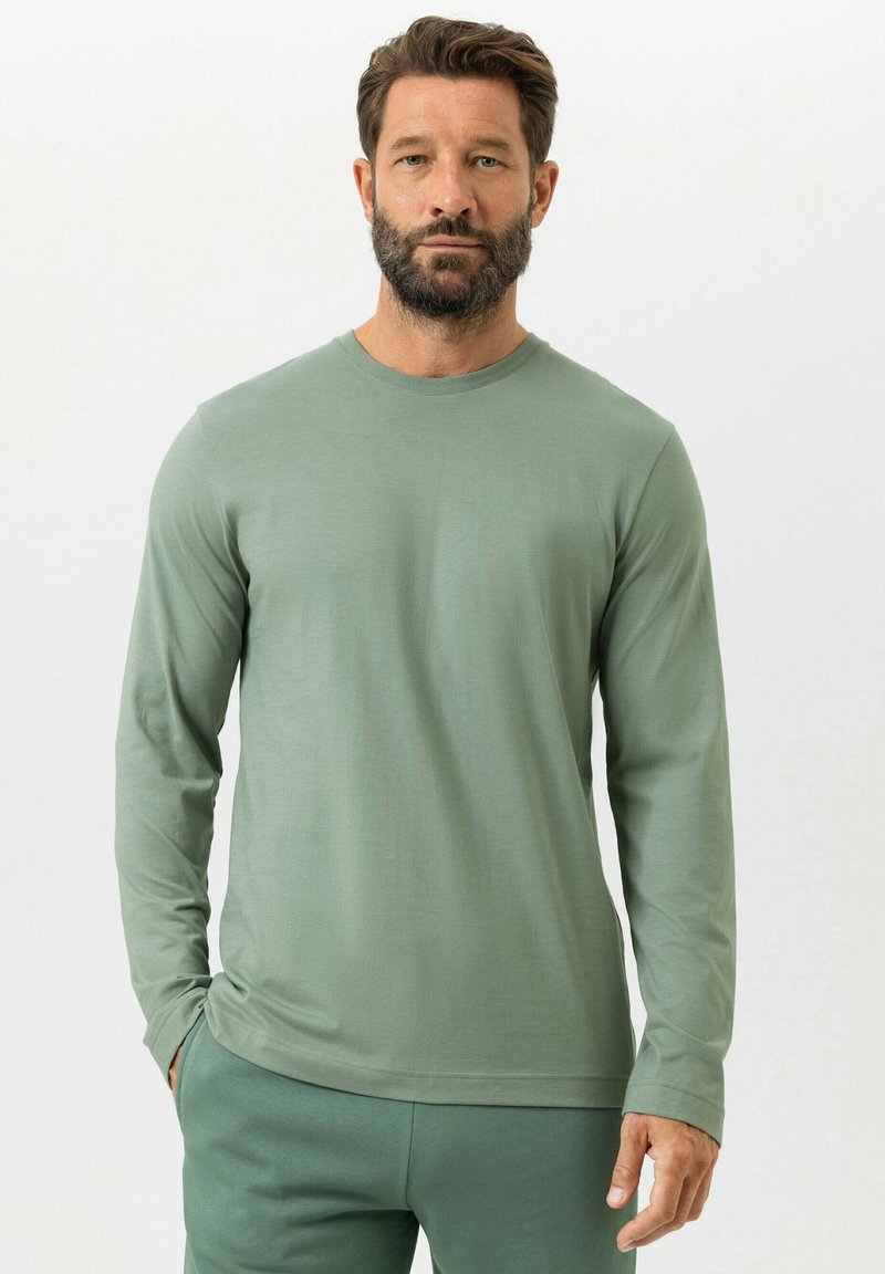 T-shirt à manches longues et col rond en tissu vert clair. Texture douce avec une coupe décontractée, associé à un pantalon de sport vert assorti.