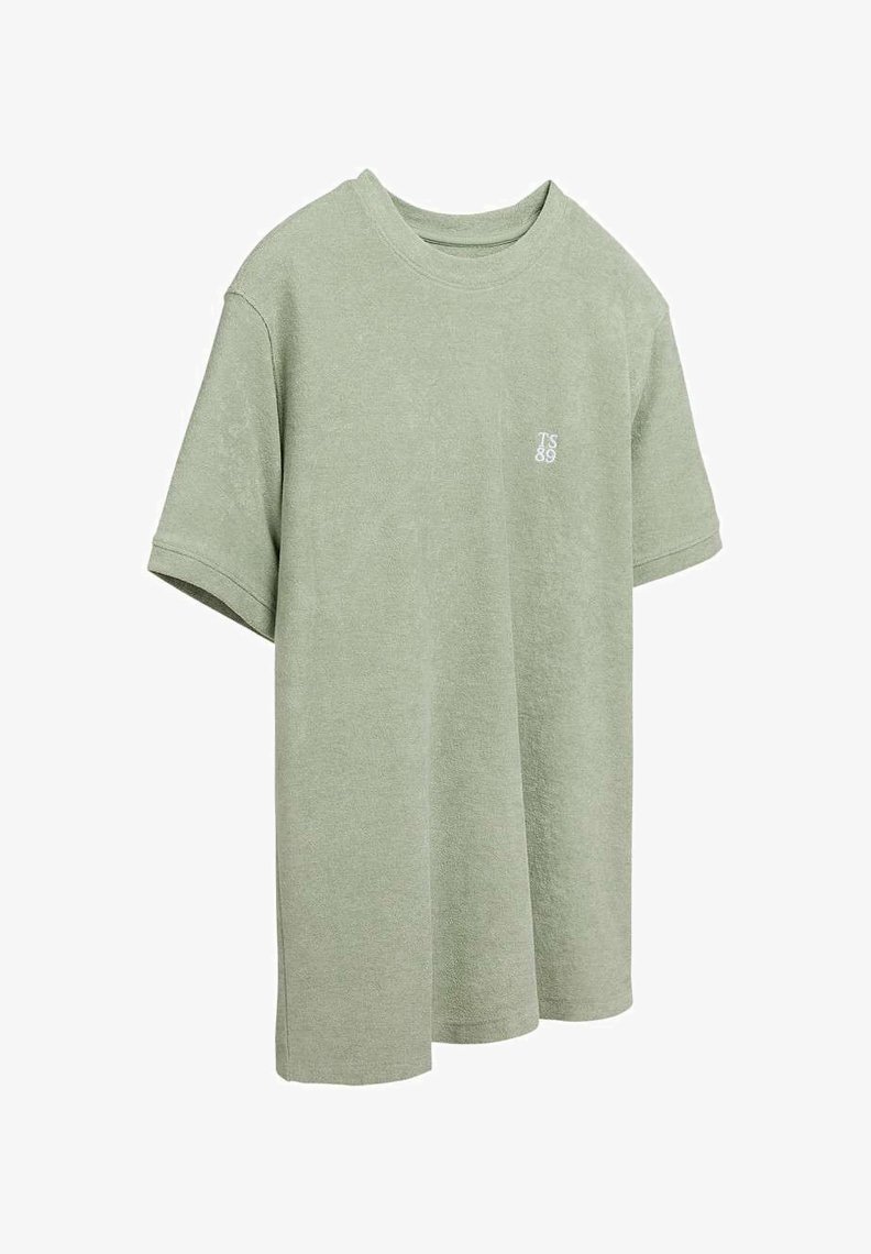 T-shirt vert clair à manches courtes avec col ras du cou, petit logo texte blanc "TS 89" sur la poitrine gauche, design uni, coupe ample.