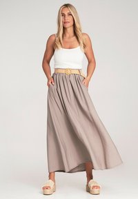 Beige Maxikleid mit Falten, einem geflochtenen Gürtel mit runder Schnalle, kombiniert mit einem weißen gerippten Tanktop und beigen Plateau-Sandalen.