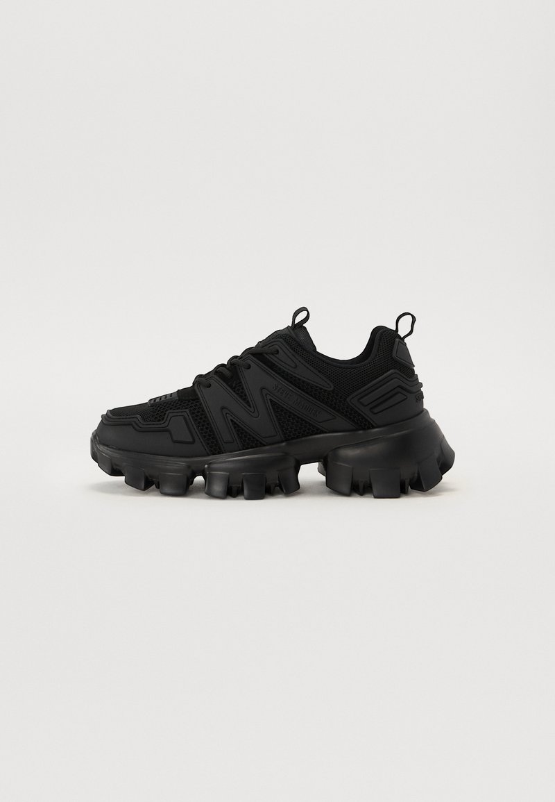 Sneaker noire avec une tige en maille texturée, une semelle épaisse et un système de laçage unique. Capte des accents en caoutchouc courbés et une languette en boucle.