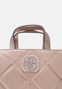 Růžová prošívaná kabelka s kovovým leskem, zdobená stříbrným geometrickým logem a dvěma krátkými uchy. Viditelný texturovaný vzor.