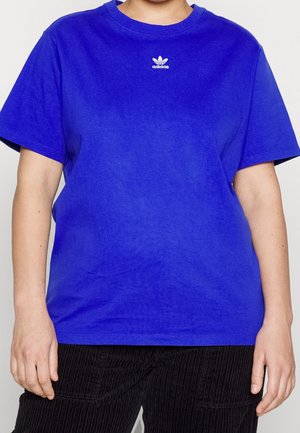 Person wearing a plain bright blue Adidas t-shirt with white logo centered near the neckline and black pants.