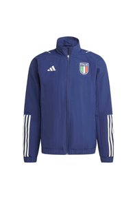 Marineblå vindjakke med høj krave, frontlynlås, Adidas-logo og "ITALIA" emblem. Har hvide tre-stribe detaljer på ærmerne.