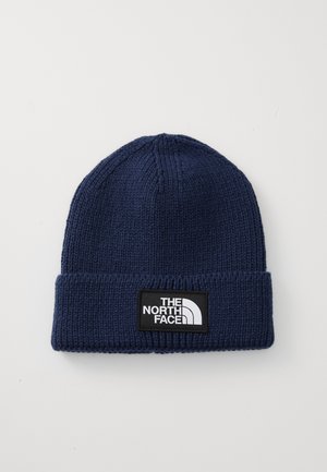 Navy blue knit beanie with folded brim featuring a rectangular black patch patch with white "The North Face" logo.