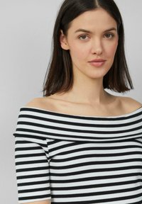 Top off-the-shoulder con sottili righe bianche e nere, texture a coste e maniche corte. Tessuto liscio con design aderente.