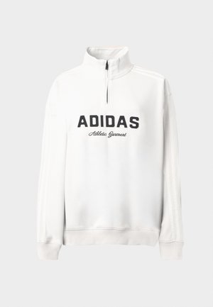 Biała sportowa bluza z połową zamka, z czarnym napisem "ADIDAS" i logo "Athletic Garment", oraz trzema białymi paskami na rękawach.