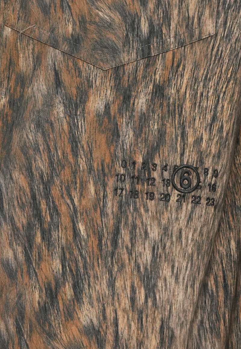 Shirt met een bruin en zwart gemêleerd patroon en bedrukte zwarte cijfers, 6 omcirkeld in een horizontale volgorde van 0-23 op de borst.