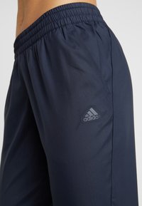 Marineblauwe sportshorts met een elastische tailleband, gemaakt van een gestructureerde stof en voorzien van een subtiele grijze Adidas-logo op de linker bovenbeen.