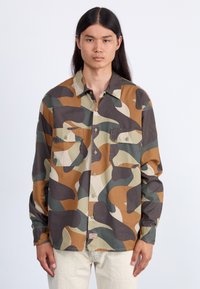 Camouflaged Hemd mit braunen, grünen und beigen abstrakten Mustern. Mit durchgehender Knopfleiste, zwei Brusttaschen und einem klassischen Kragen. Baumwollstoff.